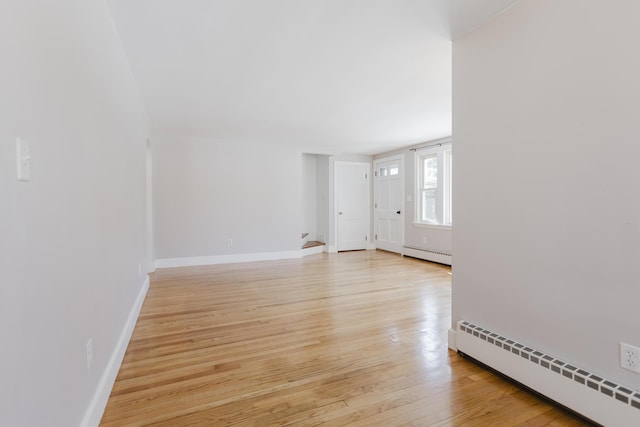 unfurnished living room featuring stairs, light wood finished floors, baseboards, and baseboard heating