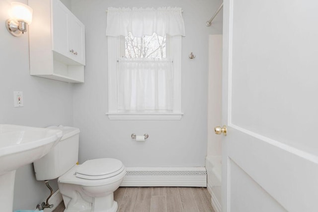 full bathroom with baseboards, baseboard heating, wood finished floors, and toilet