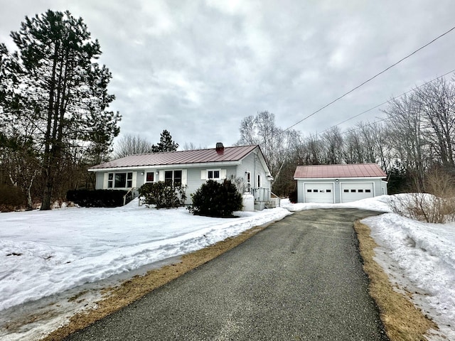 view of front of home featuring an outbuilding, a chimney, a standing seam roof, metal roof, and a garage