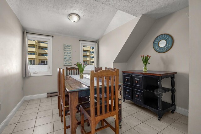 dining space with light tile patterned floors, a textured ceiling, a baseboard radiator, and baseboards