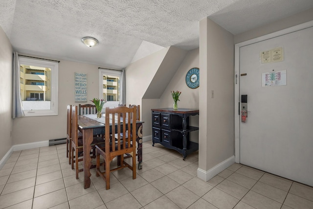 dining area with a textured ceiling, baseboards, and light tile patterned floors