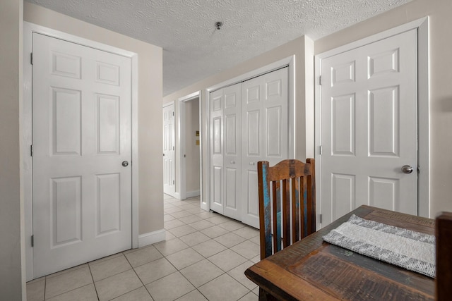 interior space with a closet, a textured ceiling, baseboards, and light tile patterned floors