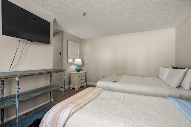 bedroom featuring a textured ceiling, carpet, and baseboards