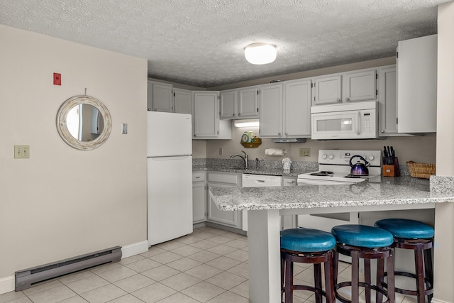 kitchen with a breakfast bar, light tile patterned floors, baseboard heating, white appliances, and a peninsula