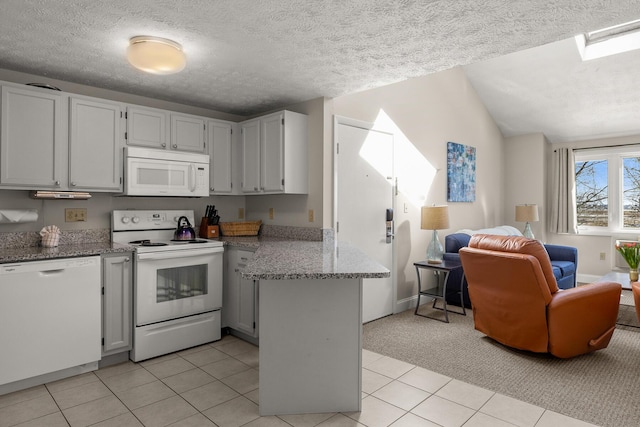 kitchen featuring white appliances, light stone counters, open floor plan, a peninsula, and vaulted ceiling