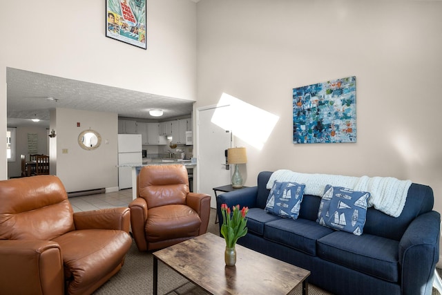 living area with a baseboard heating unit, light tile patterned floors, a textured ceiling, and a high ceiling