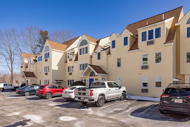 view of building exterior with uncovered parking and a residential view