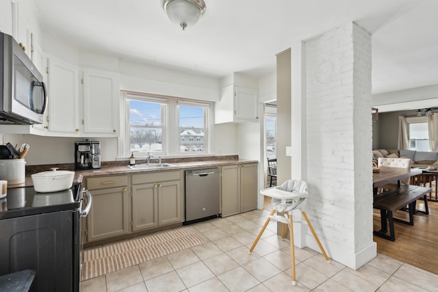 kitchen featuring electric stove, a sink, stainless steel microwave, dishwashing machine, and a healthy amount of sunlight