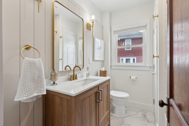 half bathroom featuring marble finish floor, toilet, vanity, and baseboards