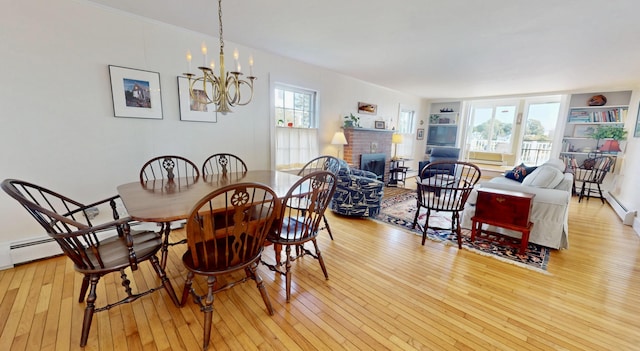 dining room featuring light wood-style floors, a fireplace, built in shelves, and an inviting chandelier