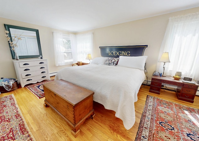 bedroom with light wood-style floors and a baseboard heating unit