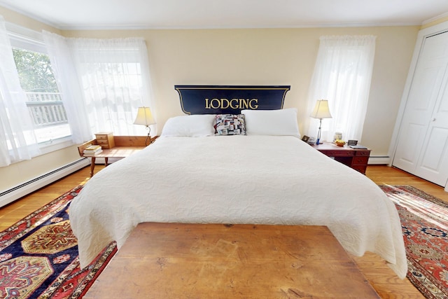 bedroom featuring crown molding, a baseboard heating unit, and wood finished floors