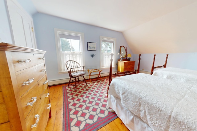 bedroom with lofted ceiling, light wood finished floors, and a baseboard heating unit