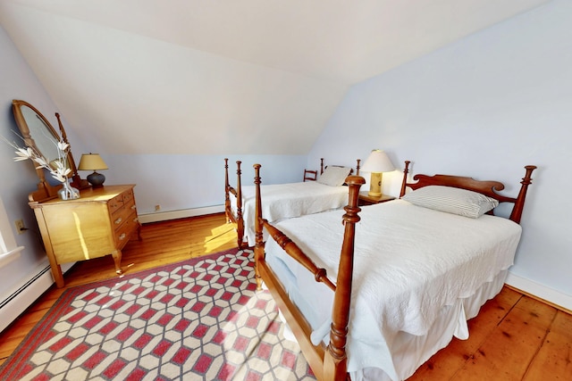 bedroom featuring lofted ceiling, a baseboard radiator, baseboards, baseboard heating, and hardwood / wood-style floors