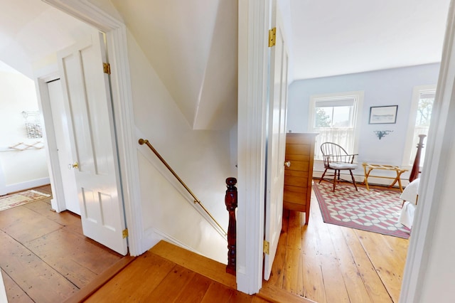 stairway with a baseboard heating unit and hardwood / wood-style floors