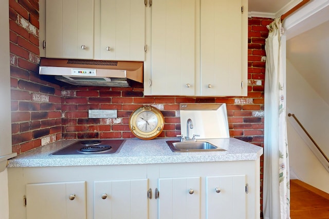 kitchen with stainless steel electric cooktop, a sink, white cabinets, and under cabinet range hood