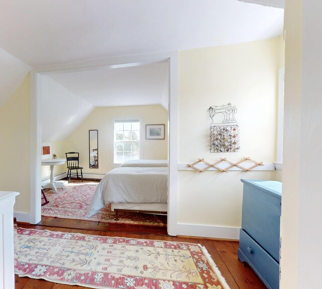 bedroom featuring lofted ceiling, baseboards, and hardwood / wood-style floors