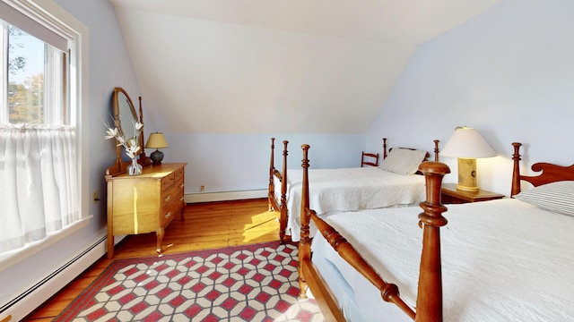 bedroom with a baseboard heating unit, vaulted ceiling, baseboard heating, and wood finished floors