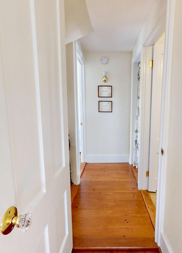 hall with light wood-style flooring and baseboards