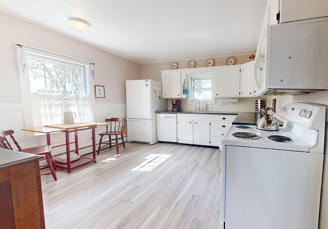 kitchen featuring light wood-style flooring, wainscoting, a sink, white cabinets, and white appliances