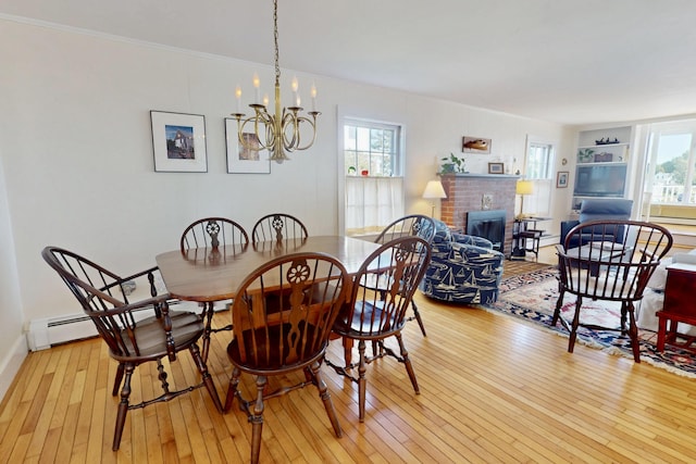 dining room featuring a baseboard heating unit, light wood-style flooring, a chandelier, and ornamental molding