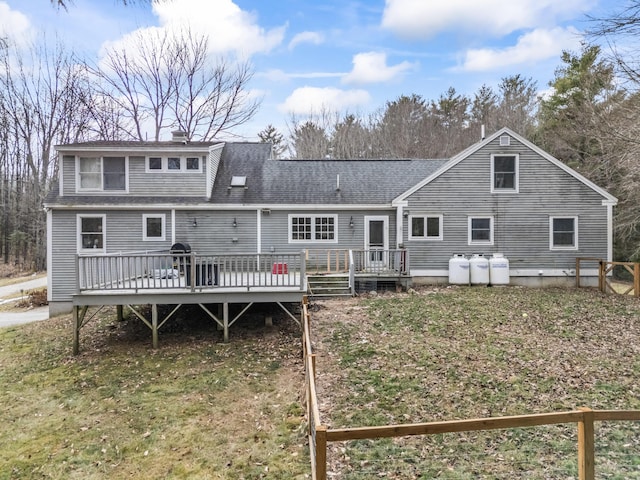 rear view of property featuring a wooden deck, a yard, and roof with shingles