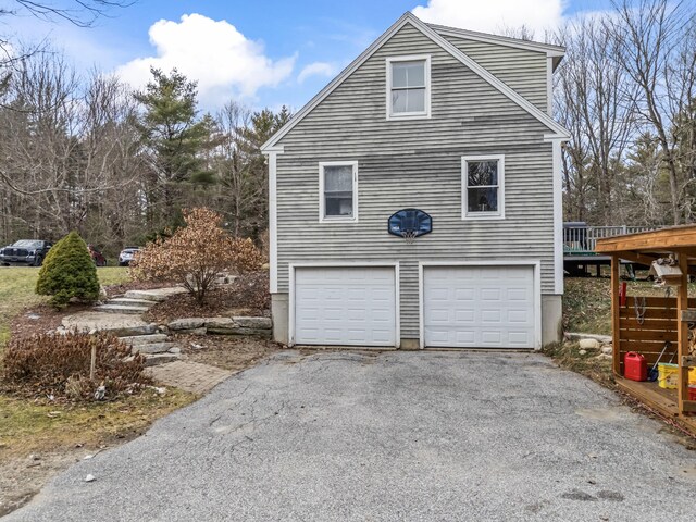 view of side of property featuring stairs, an attached garage, and driveway