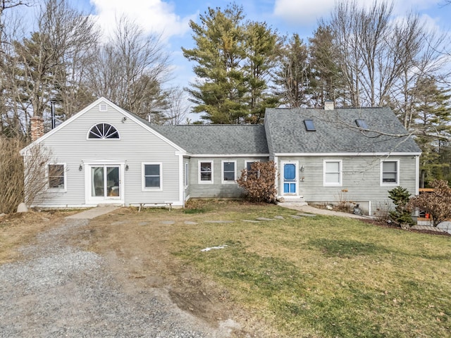 rear view of house with dirt driveway, a lawn, roof with shingles, and a chimney