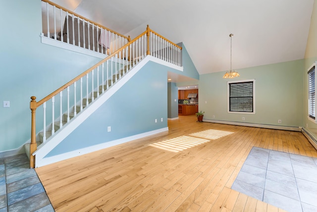 unfurnished living room featuring a baseboard heating unit, baseboards, stairs, hardwood / wood-style flooring, and high vaulted ceiling