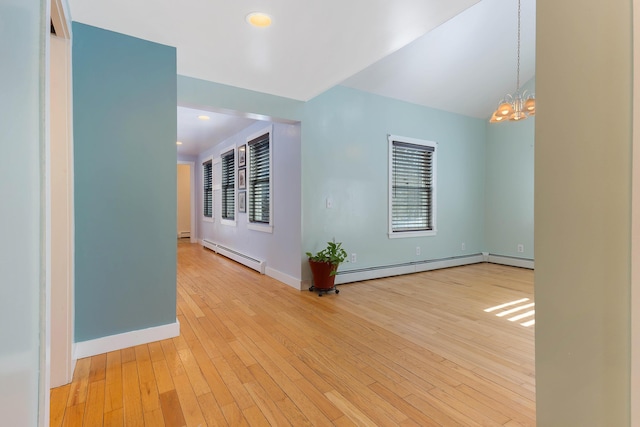 empty room featuring a chandelier, a baseboard heating unit, baseboards, and wood-type flooring