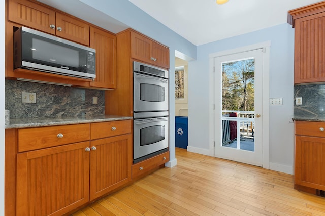 kitchen featuring light wood-style floors, tasteful backsplash, appliances with stainless steel finishes, and brown cabinets