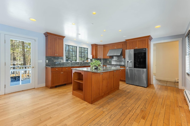 kitchen with light wood-style floors, stainless steel fridge, under cabinet range hood, and brown cabinets