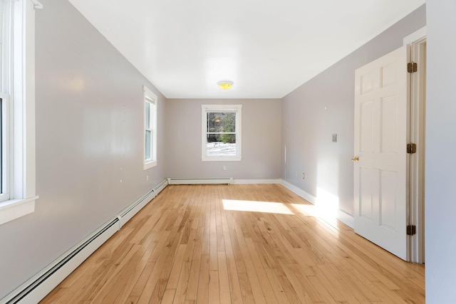 unfurnished room featuring baseboard heating, baseboards, and light wood-style floors