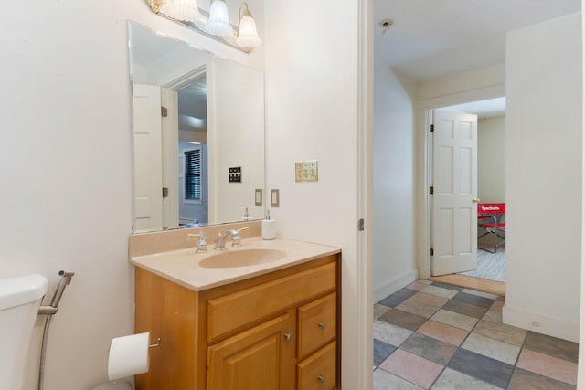 half bathroom featuring vanity, toilet, and baseboards