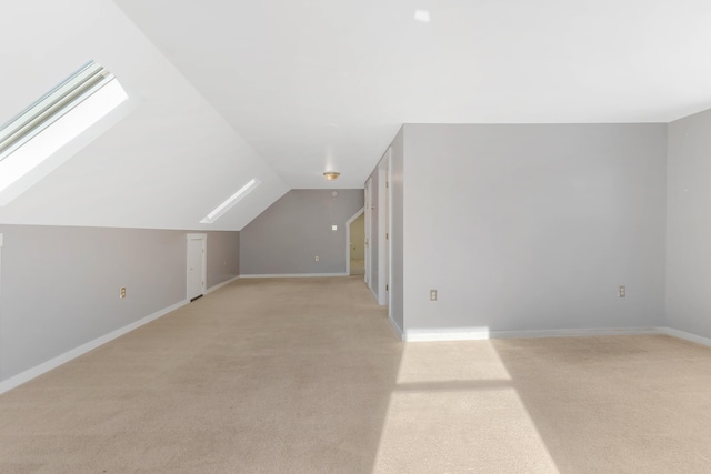 bonus room featuring lofted ceiling with skylight, baseboards, and light carpet