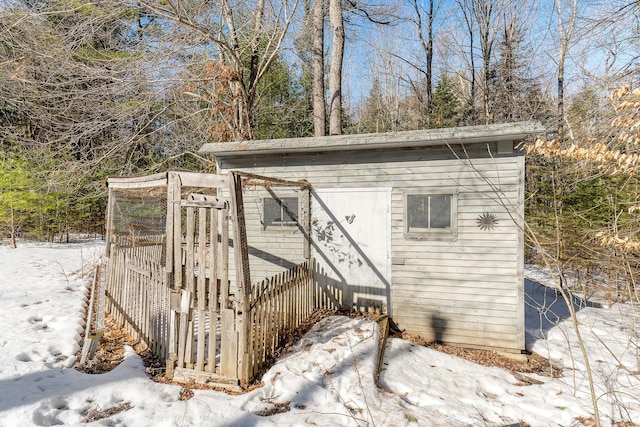 snow covered structure with an outbuilding