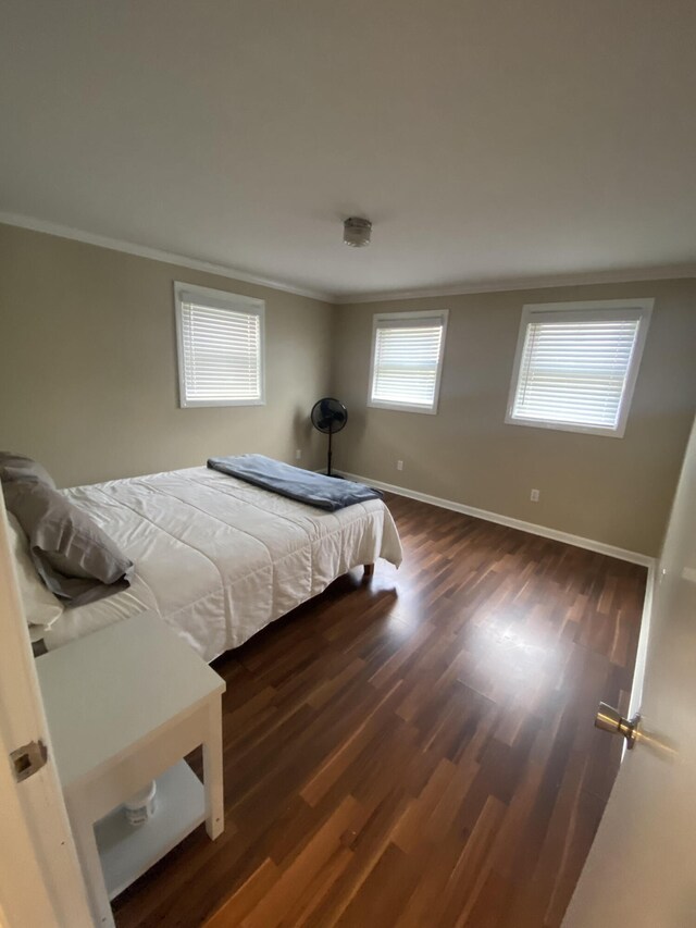 bedroom with baseboards, wood finished floors, and ornamental molding