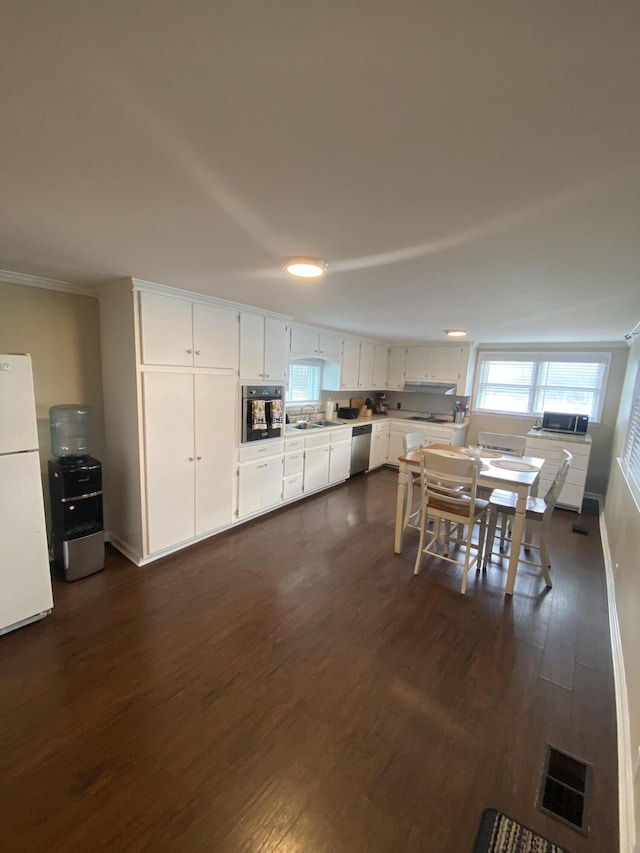 kitchen featuring visible vents, black oven, a sink, freestanding refrigerator, and stainless steel dishwasher