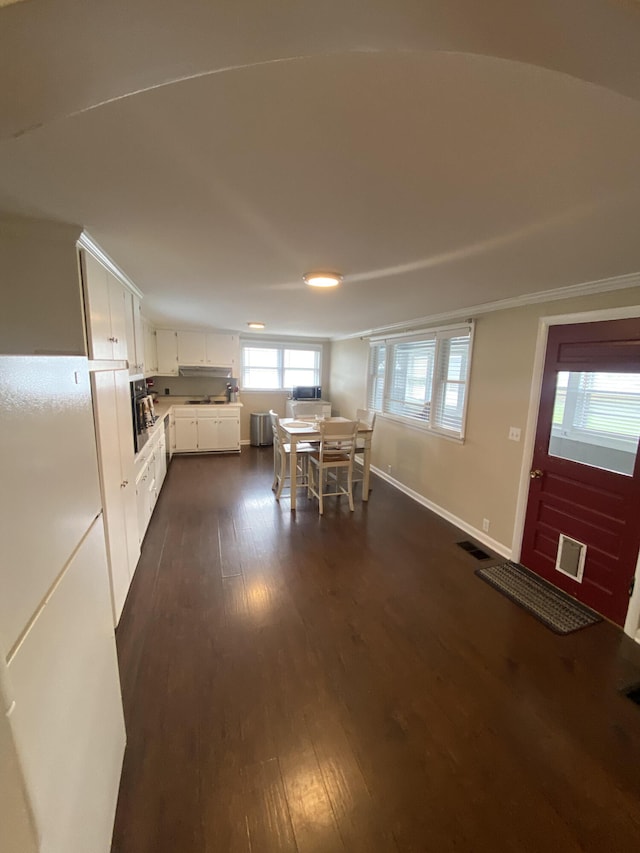 unfurnished dining area with dark wood finished floors, baseboards, and visible vents