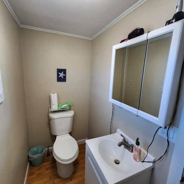 half bathroom featuring baseboards, toilet, ornamental molding, wood finished floors, and vanity