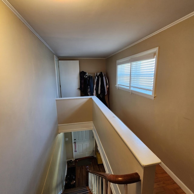 stairway with crown molding, wood finished floors, and baseboards