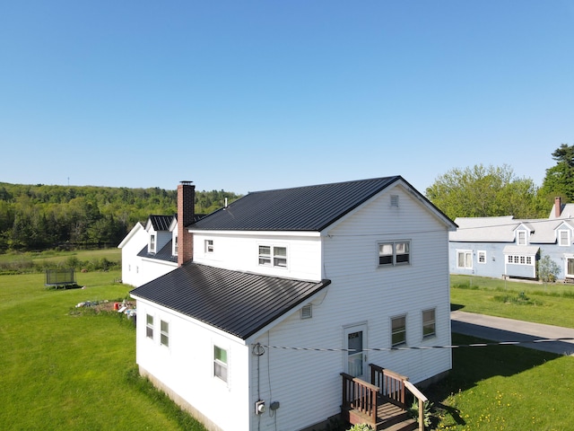 26 Purple Heart Hwy, Brooks, ME 04921 - rear view of house with a standing seam roof, a chimney, metal roof, and a yard