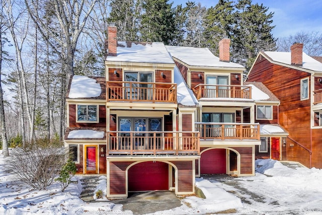 view of front of property with a chimney, an attached garage, and a balcony