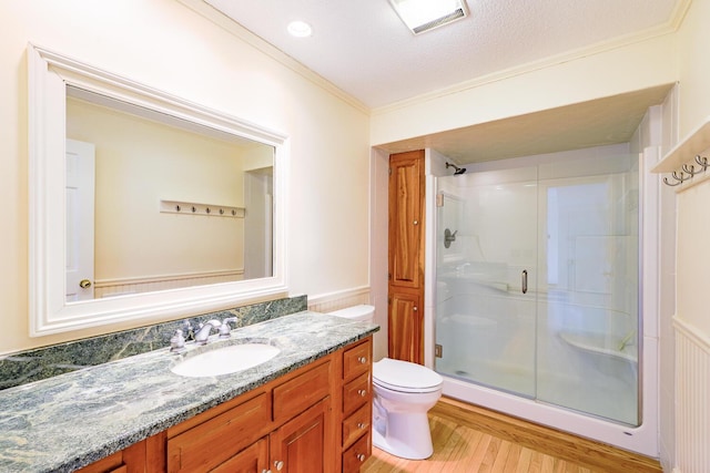 full bath with toilet, ornamental molding, a shower stall, vanity, and wood finished floors