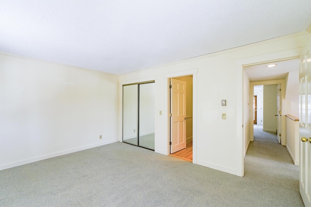 unfurnished bedroom with light carpet, a closet, and baseboards