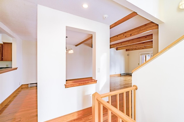 hall with light wood-style floors, recessed lighting, a baseboard heating unit, and beamed ceiling