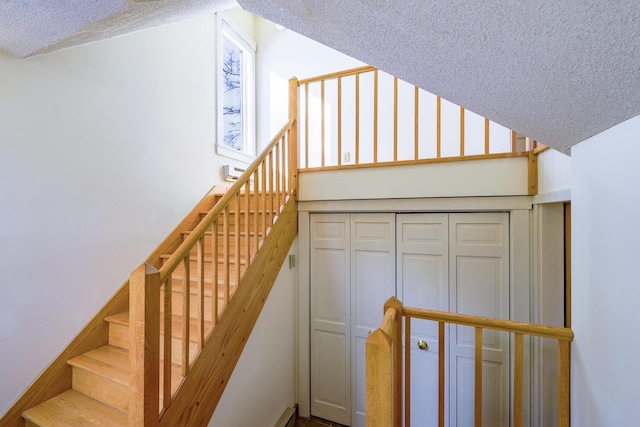 staircase featuring lofted ceiling and a textured ceiling