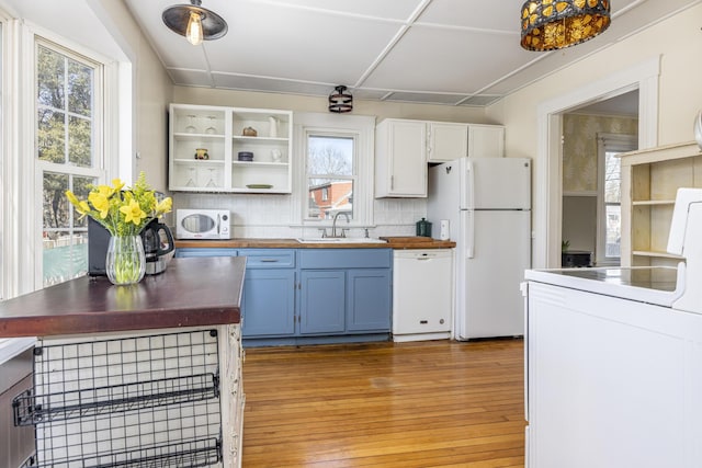 kitchen with a sink, blue cabinetry, butcher block counters, white appliances, and open shelves