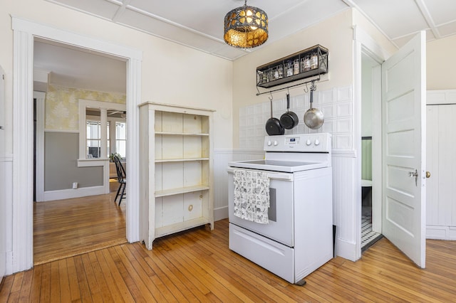 kitchen with a wainscoted wall, light wood-style flooring, and white electric stove