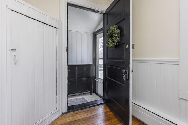 foyer entrance featuring a wainscoted wall, baseboard heating, and hardwood / wood-style flooring